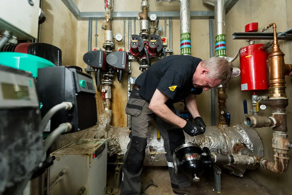 Engineer fixing a pump surrounded by pipes